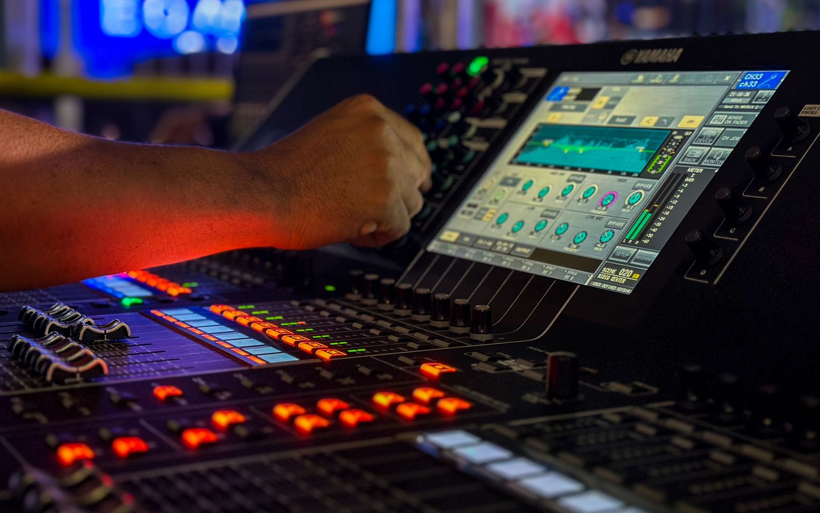 Live event technician adjusting controls on a digital audio mixing console