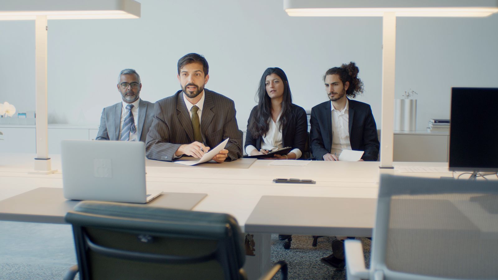 Four colleagues facing a laptop during a video conference in a bright meeting room