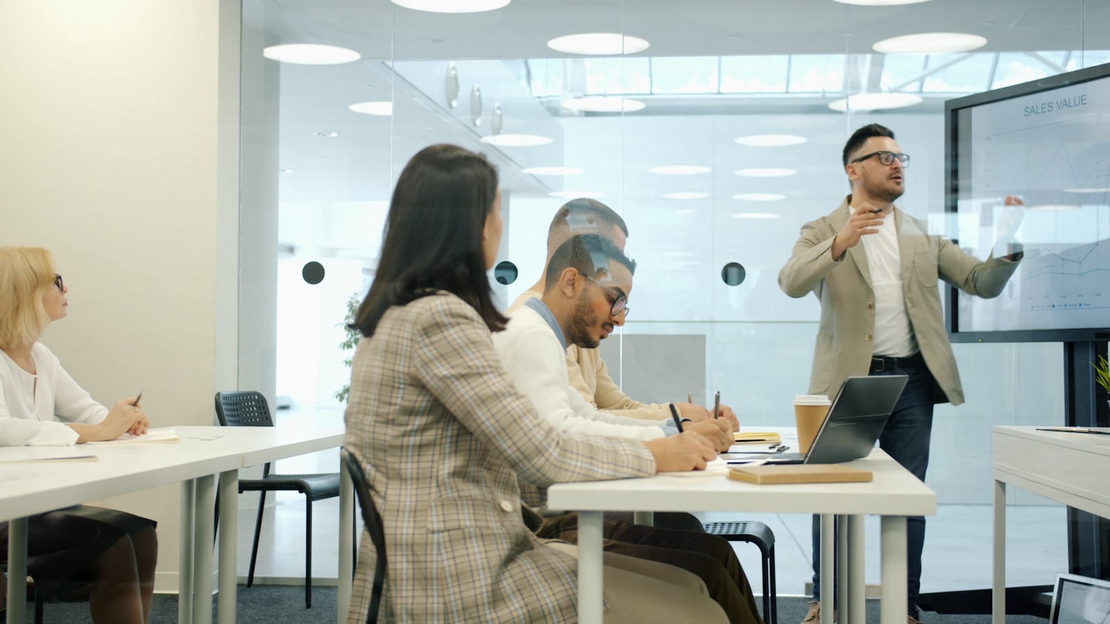 Presenter explaining a chart on a large display to colleagues in a modern office